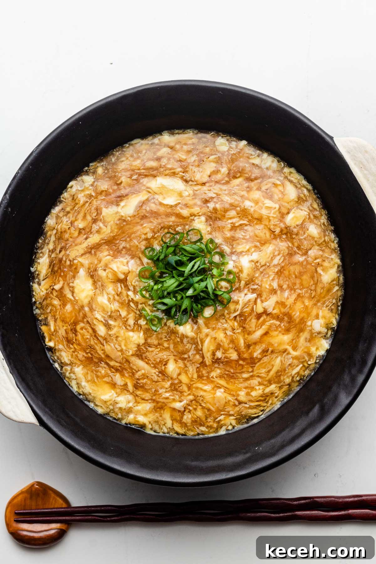 thick egg sauce over udon noodles in a black bowl