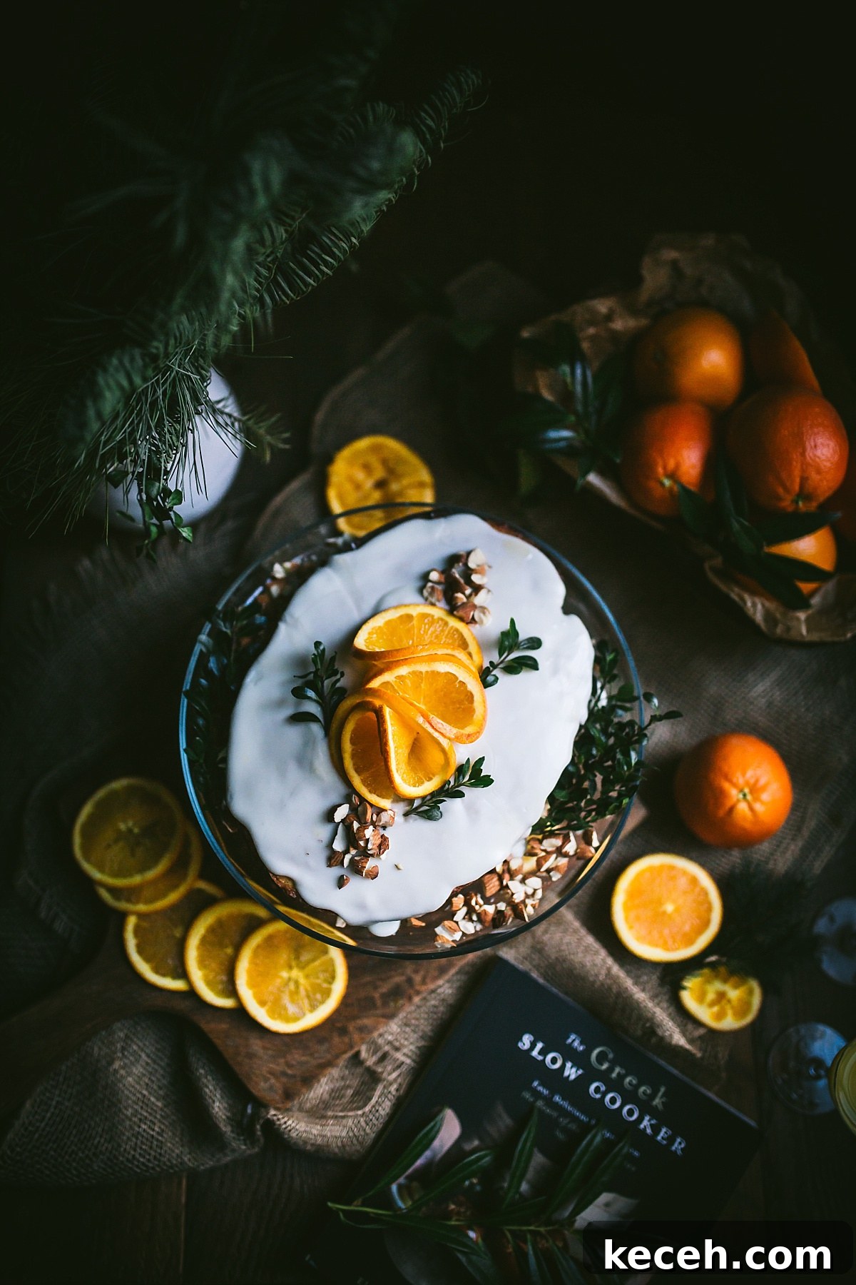 Vasilopita (Greek New Year Cake) — Slow Cooker or Oven Recipe 9 Flatlay shot of Vasilopita before it is cut and is topped with decorative orange slices and almond pieces.