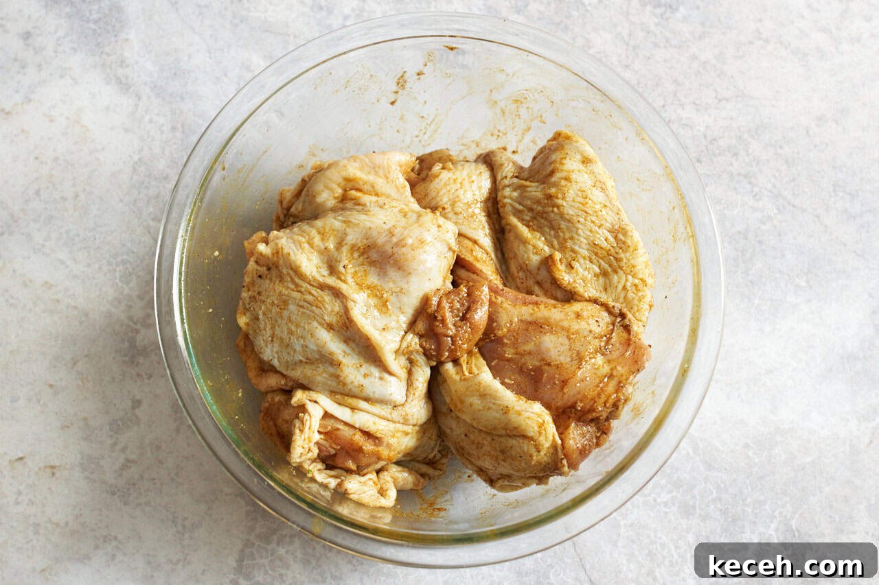 Skillet Chicken Tagine with Apricots and Warm Spices 4 Chicken thighs coated in spices in a glass bowl.