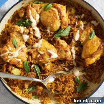 A pan of chicken shawarma and rice topped with mint leaves with a spoon in it.