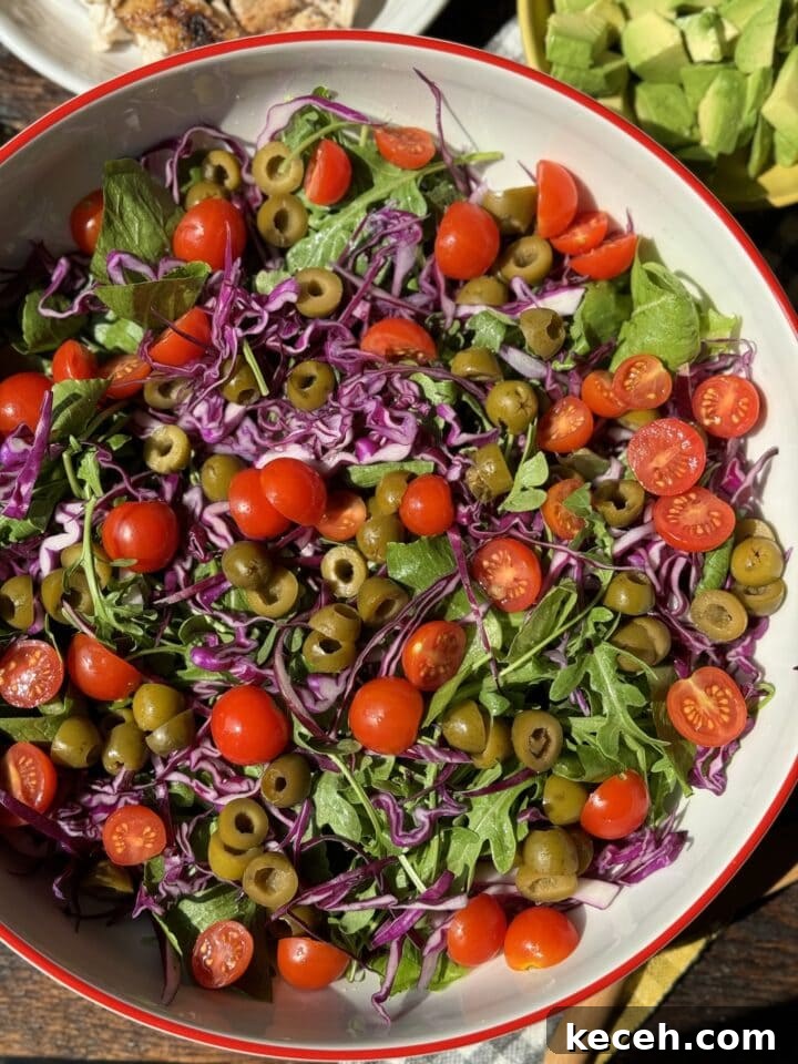 Fresh garden salad with cherry tomatoes, green olives, purple cabbage, and arugula. Perfect for a healthy meal or side dish.