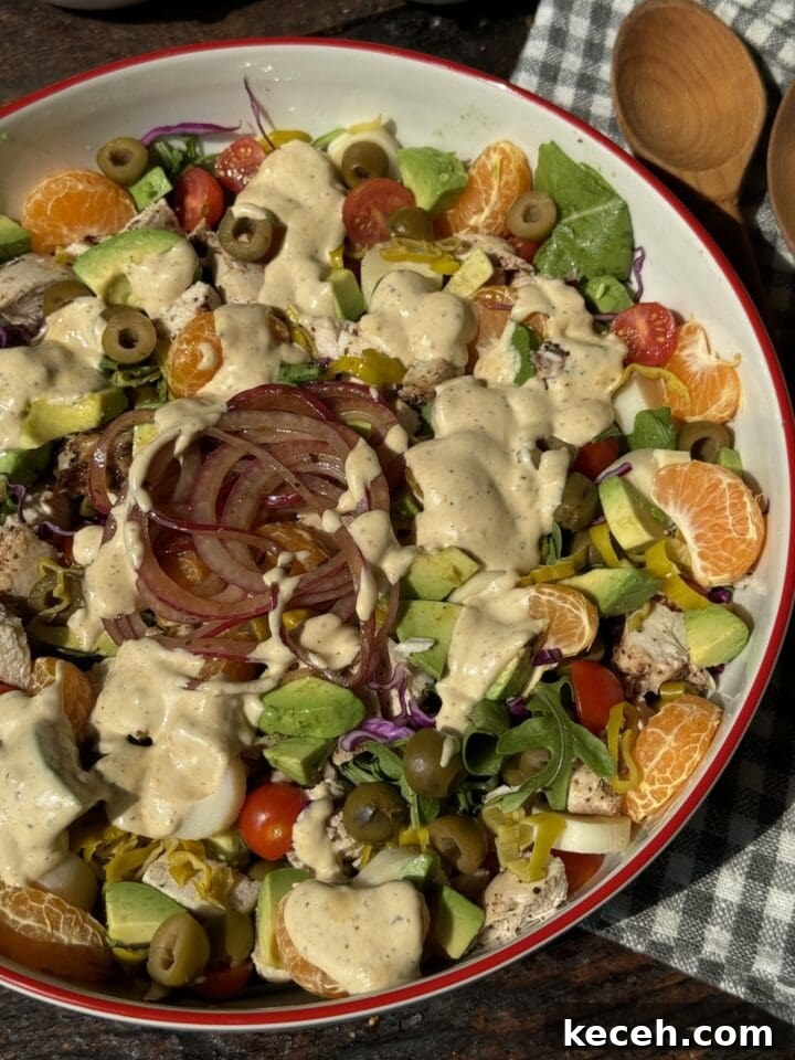 Fresh colorful salad with avocado, cherry tomatoes, red onion, olives, and creamy dressing - NoCrumbsLeft.