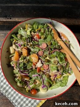 Fresh garden vegetable salad with colorful greens, cherry tomatoes, and olives, served in a rustic bowl.