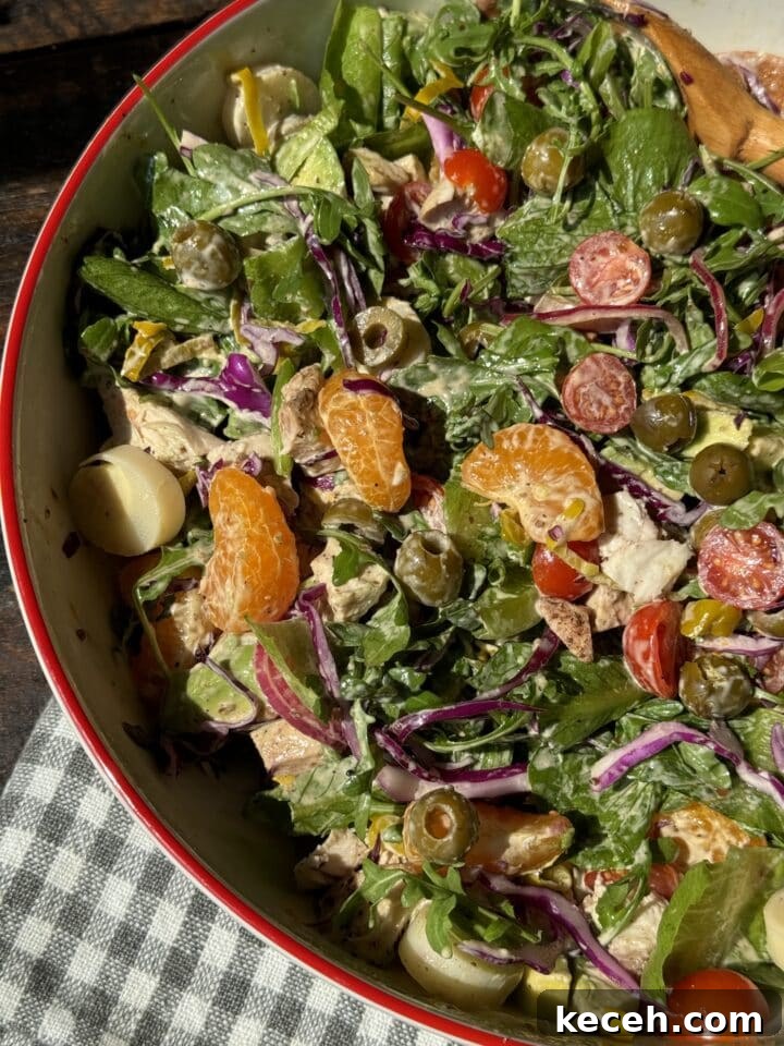 salad with olives clementines cherry tomatoes chicken hearts of palm cabbage and romaine in a large bowl