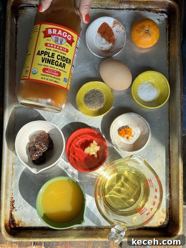 Apple cider vinegar bottle on a metal tray with spices, eggs, citrus, and other ingredients for healthy recipes.