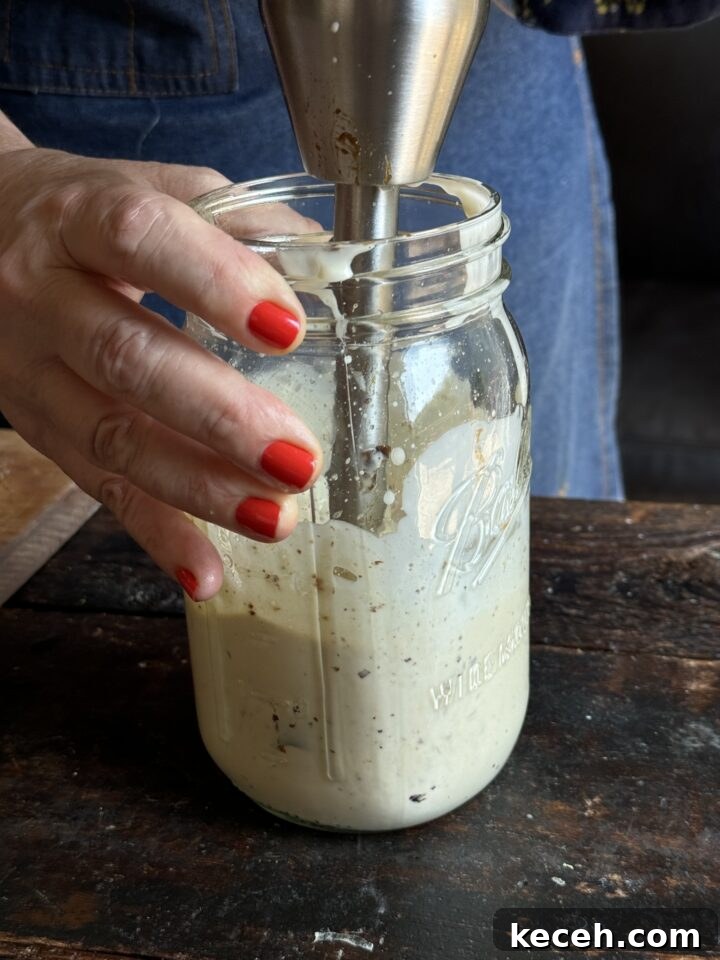 Creamy homemade mayonnaise being blended in a jar with an immersion blender.