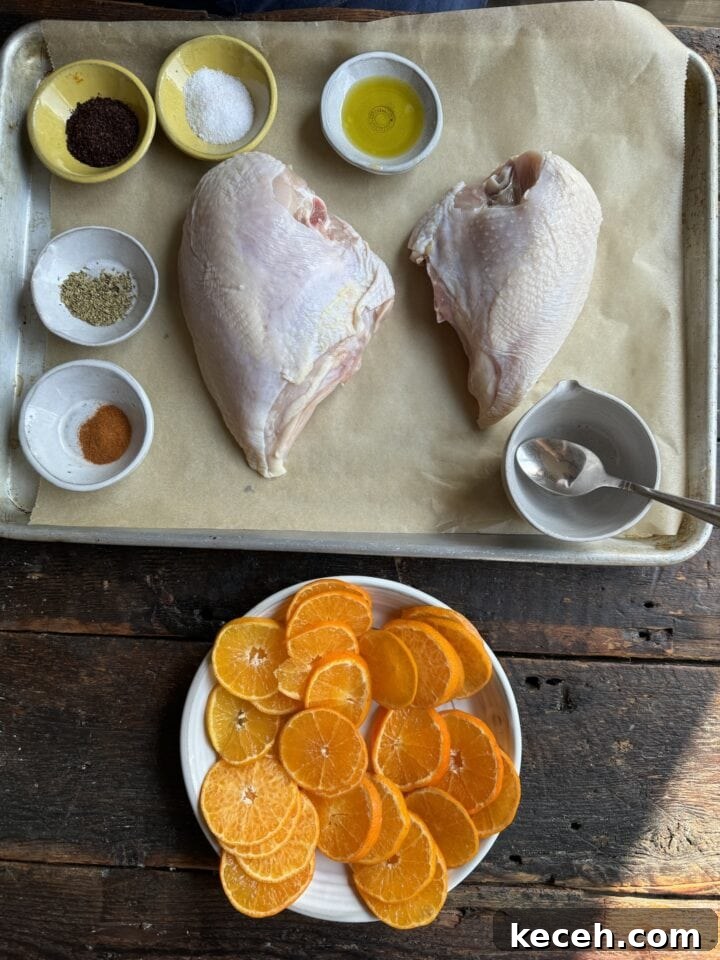 Juicy raw chicken thighs with seasoning and fresh orange slices, ready for cooking on rustic wood table.