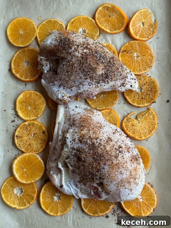 Juicy roasted chicken breasts with orange slices and spices on baking sheet. Perfect for healthy meal prep beginner recipes.