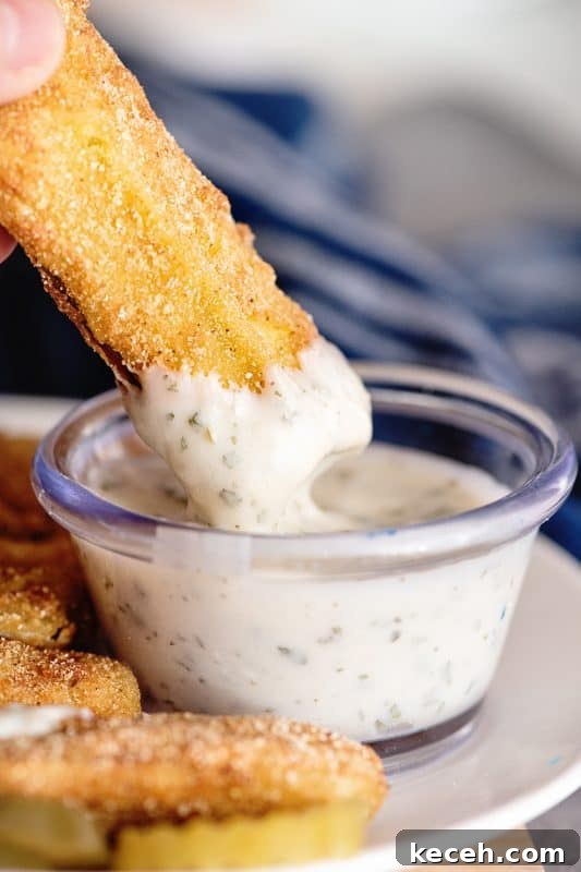 Crispy Fried Dill Pickles with Tangy Dipping Sauce 2 dipping fried dill pickle into ranch dressing.