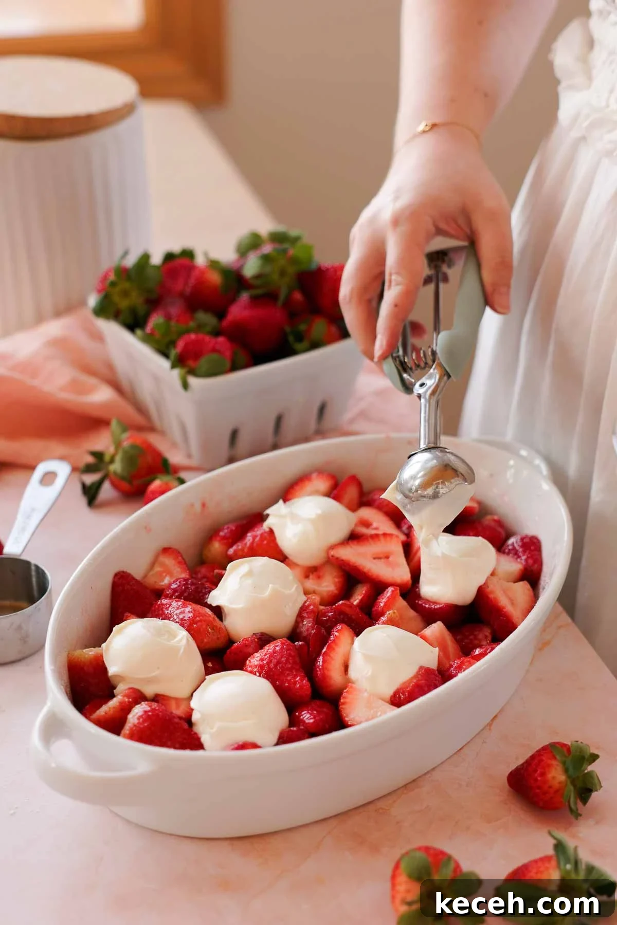 Cream Cheese Strawberry Cobbler Recipe — Sweet Rustic Dessert 7 scooping cheesecake filling onto strawberry filling in cobbler pan