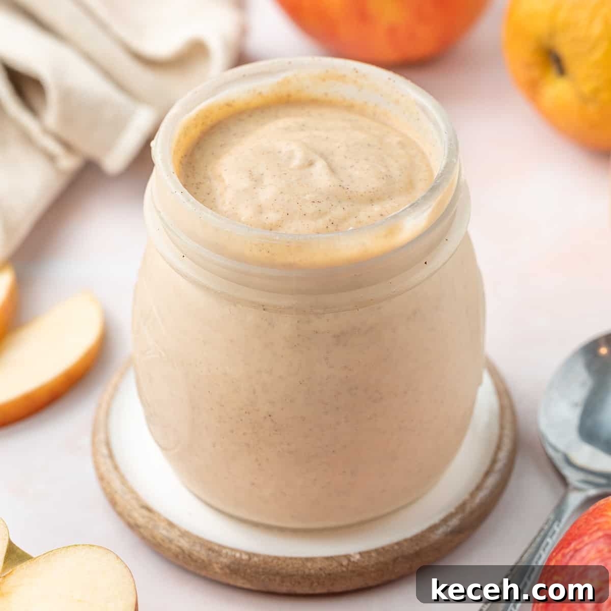 Apple Curd Recipe: Smooth Homemade Apple Spread 2 Curd in a preserve jar surrounded by apples and apple slices.