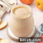 Apple Curd Recipe: Smooth Homemade Apple Spread 8 Curd in a preserve jar surrounded by apples and apple slices.