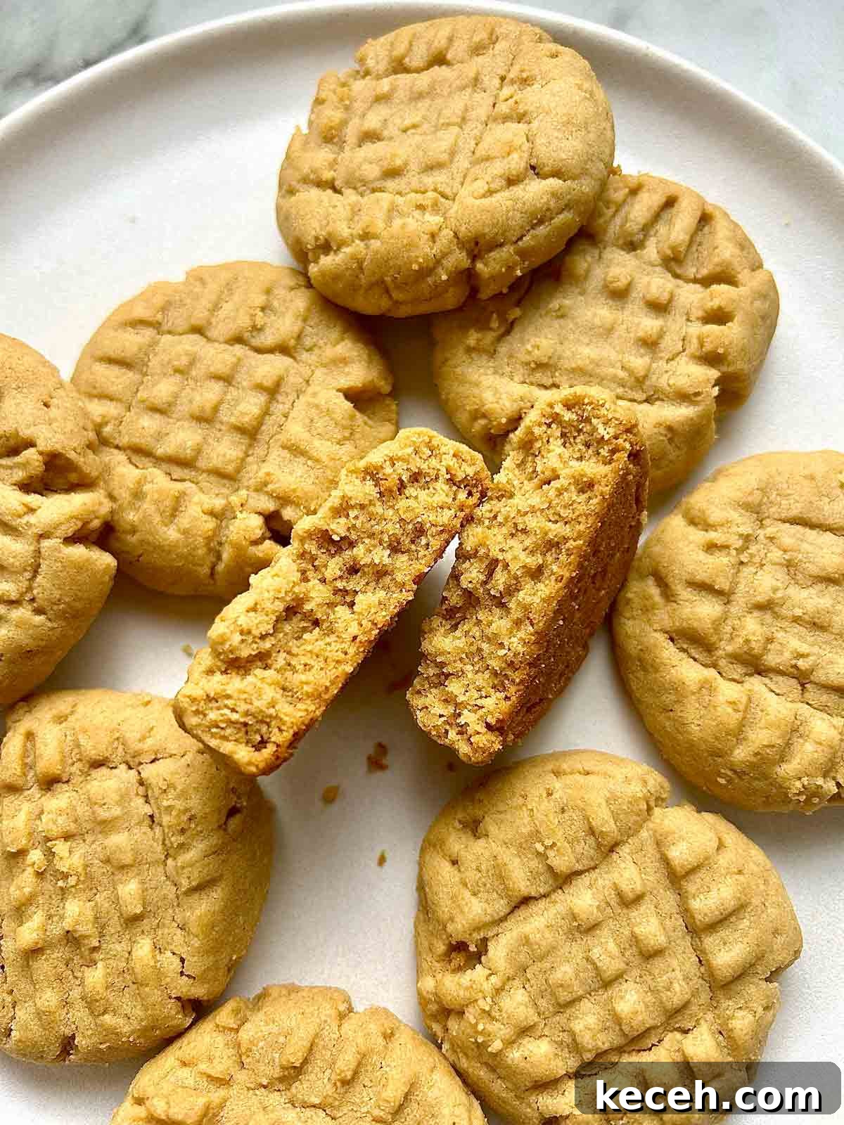 Chewy Peanut Butter Cookies Recipe with Crispy Edges 3 close up of peanut butter cookies on plate; one cookie is split in half to show the crumb.
