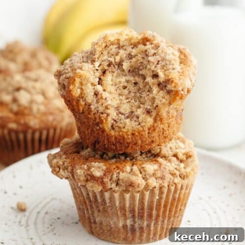 A stack of two banana coffee cake muffins, one has a bite taken out of it.