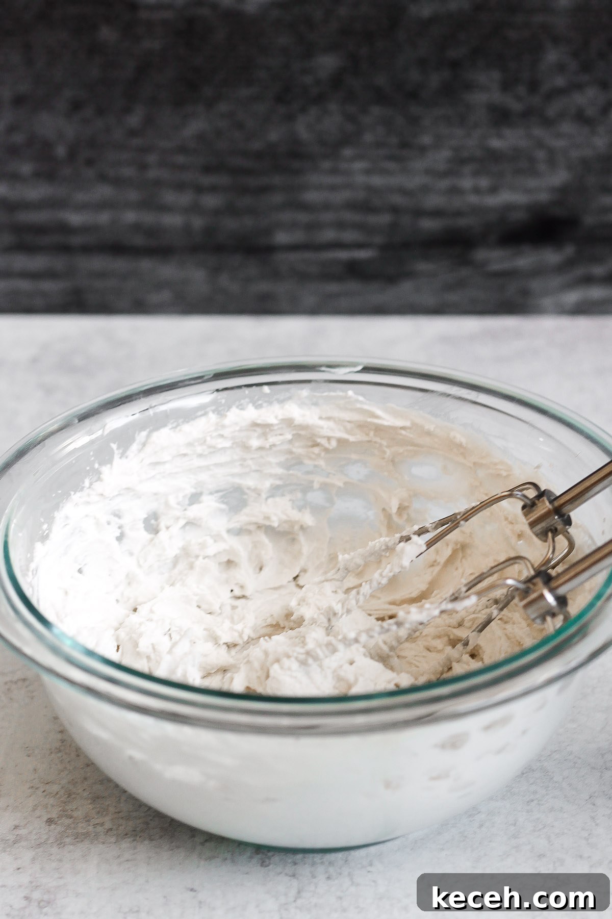 Coconut Whipped Cream Recipe: Light, Dairy-Free Topping 5 side angle view of coconut whipped cream in glass mixing bowl with electric mixer whisks