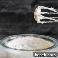 electric beater with whipped coconut cream standing over mixing bowl