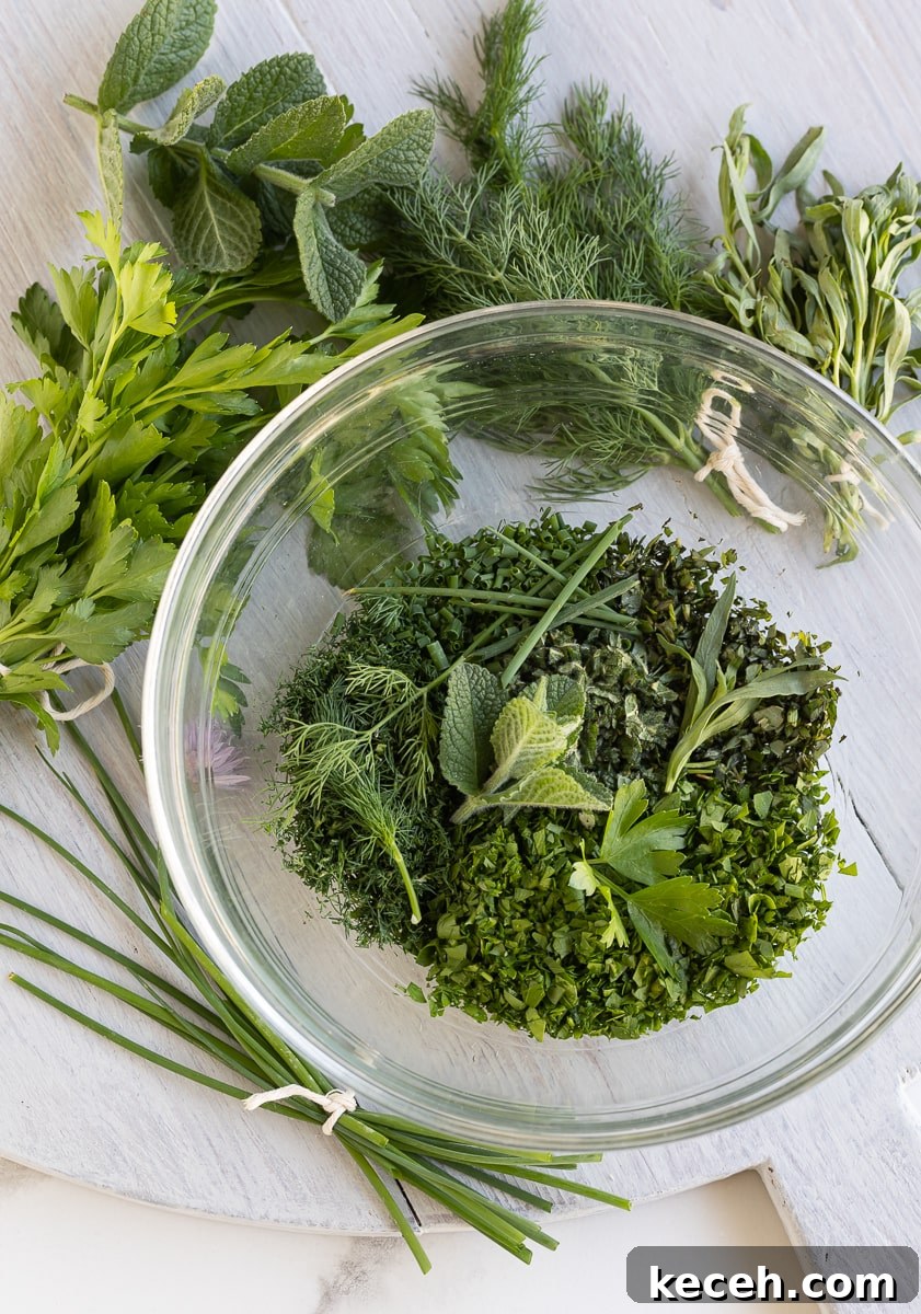Creamy Green Goddess Dressing & Herb Dip Recipe 4 Fresh herbs for Green Goddess dressing in a glass bowl on a gray board.