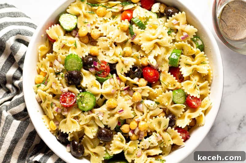 Overhead shot of a large white bowl filled with ingredients to make chickpea pasta salad