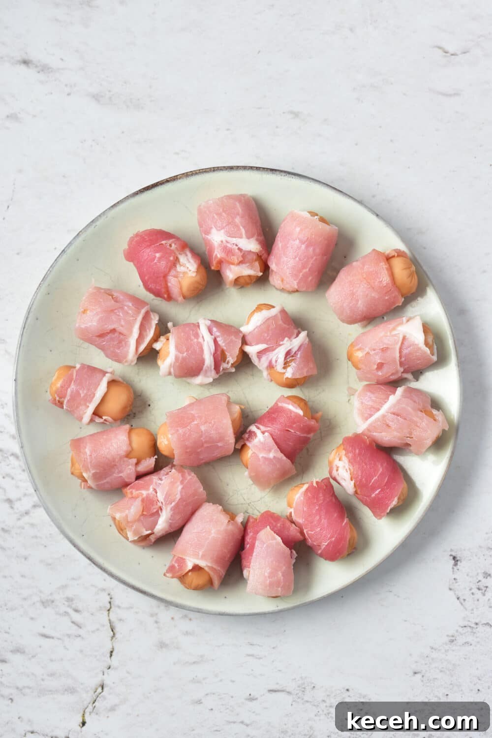 pigs in a blanket ready for oven on round plate, overhead view