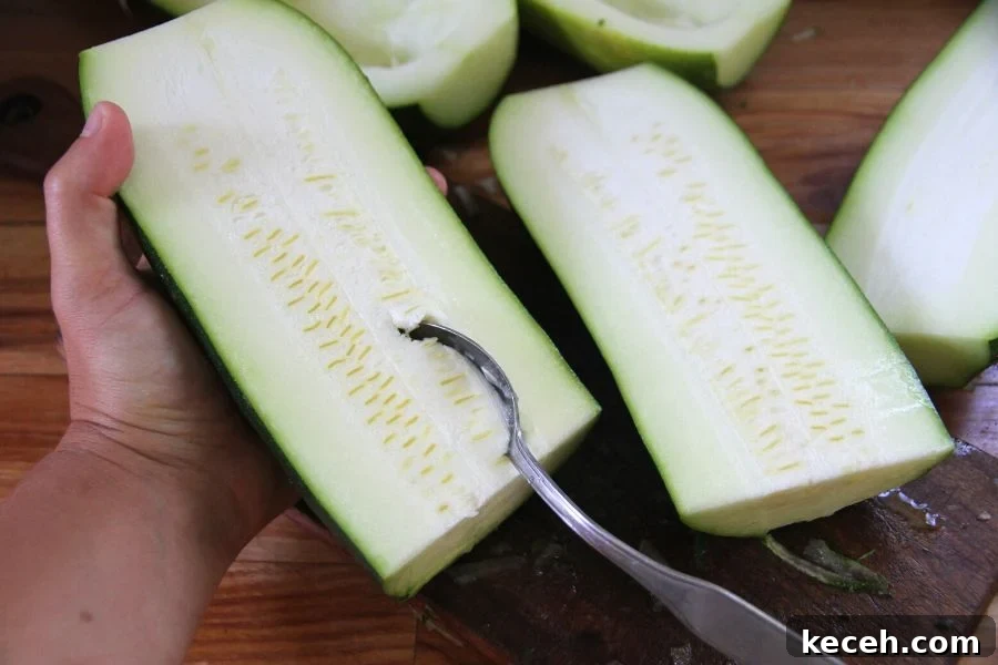 Freeze Fresh Zucchini from the Garden: Step-by-Step Guide for Crispy Texture 3 holding a halved zucchini and scraping out the soft center with a spoon