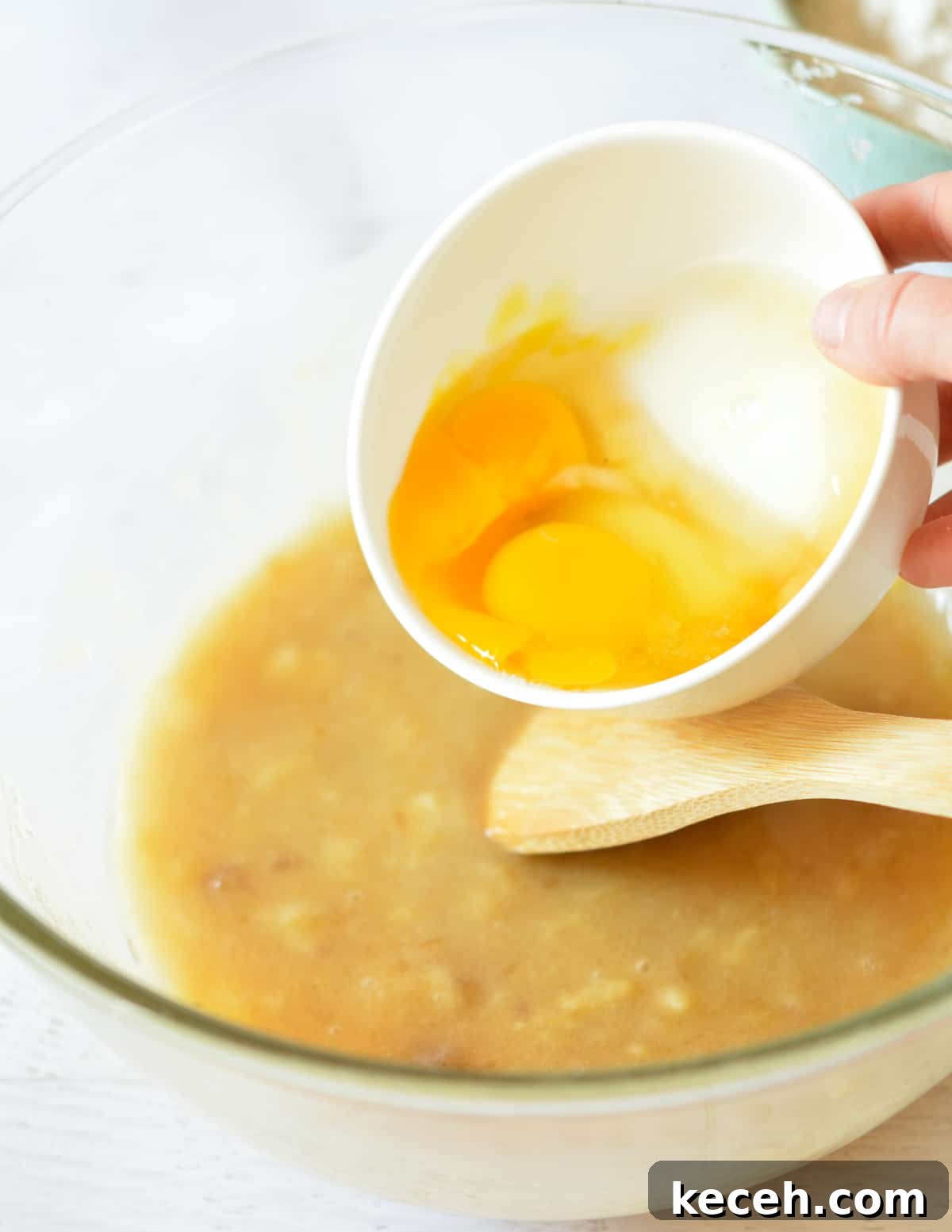Moist Banana Bread Made with Frozen Bananas 8 pouring eggs into a bowl of mashed bananas and sugar.