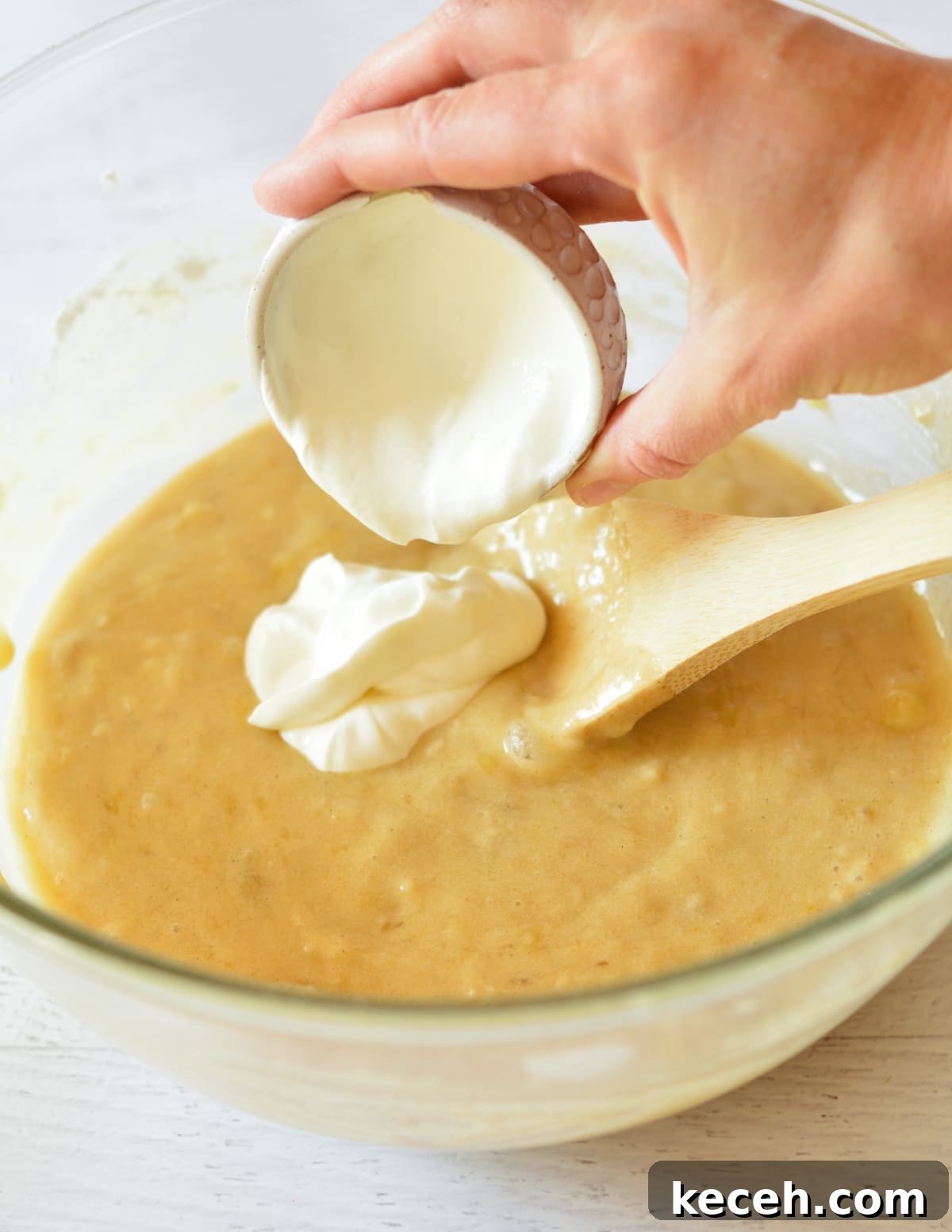 Moist Banana Bread Made with Frozen Bananas 10 pouring sour cream into banana bread batter.