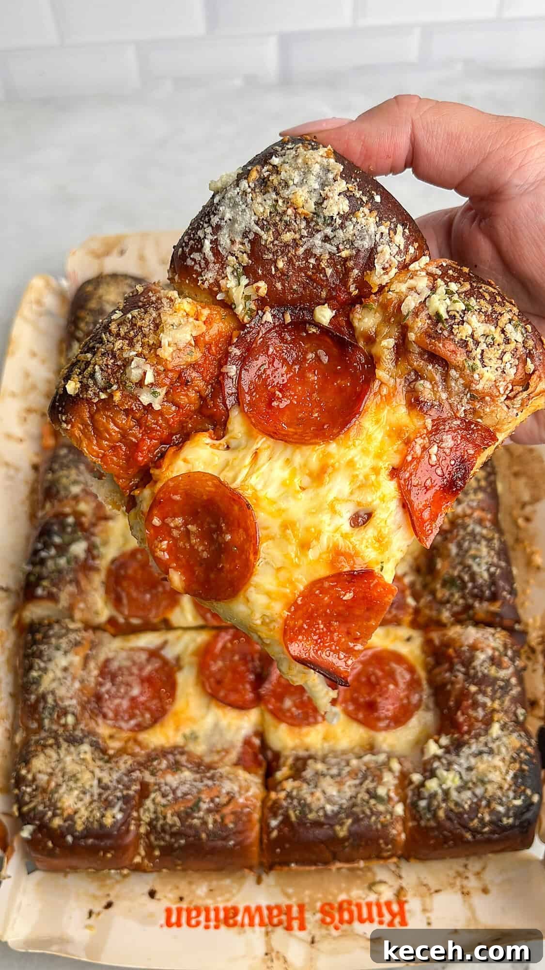 Hawaiian roll pizza slice being held in hand