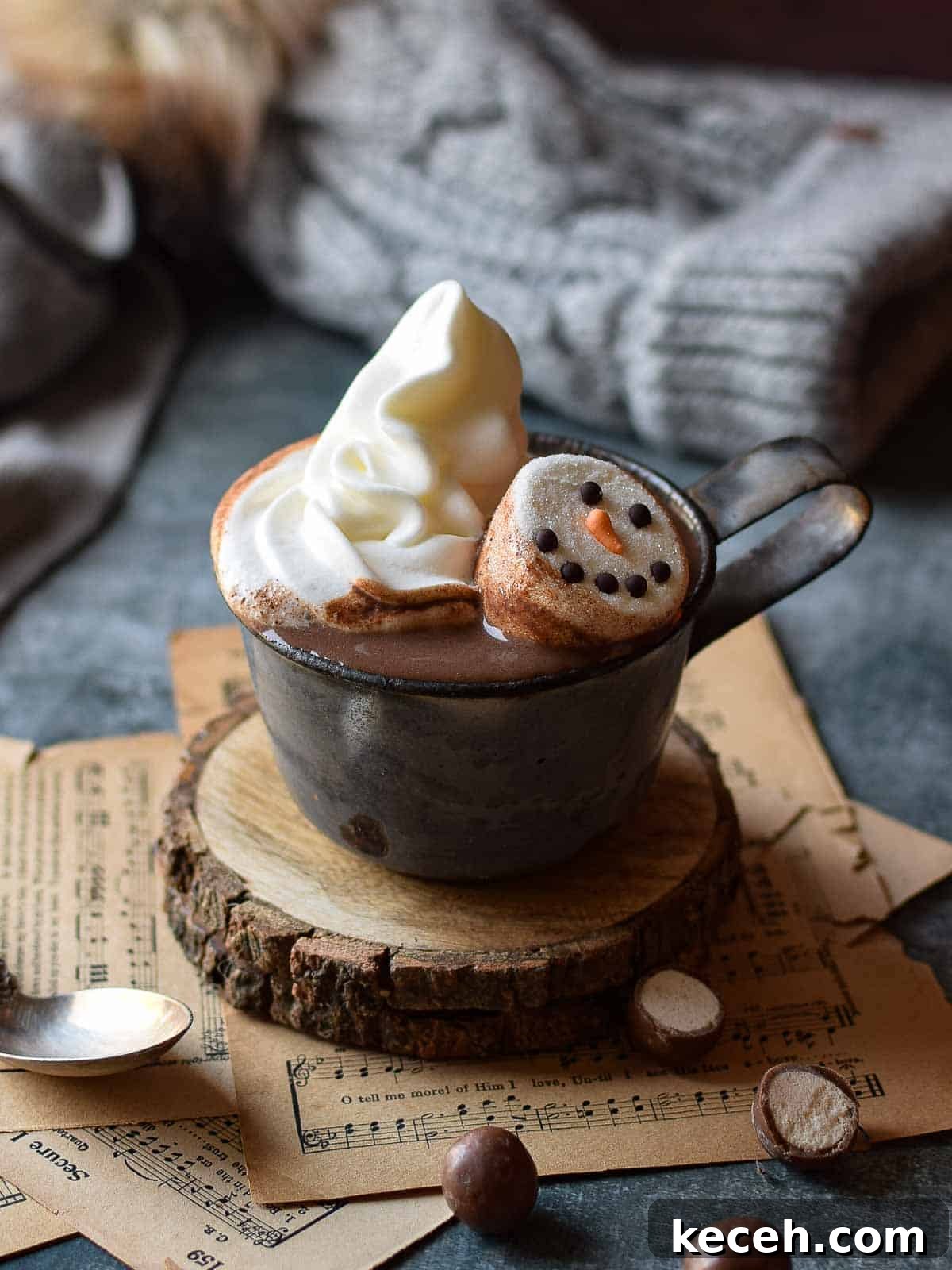 Malted milk hot chocolate in a grey mug with whipped cream and snowman marshmallows.