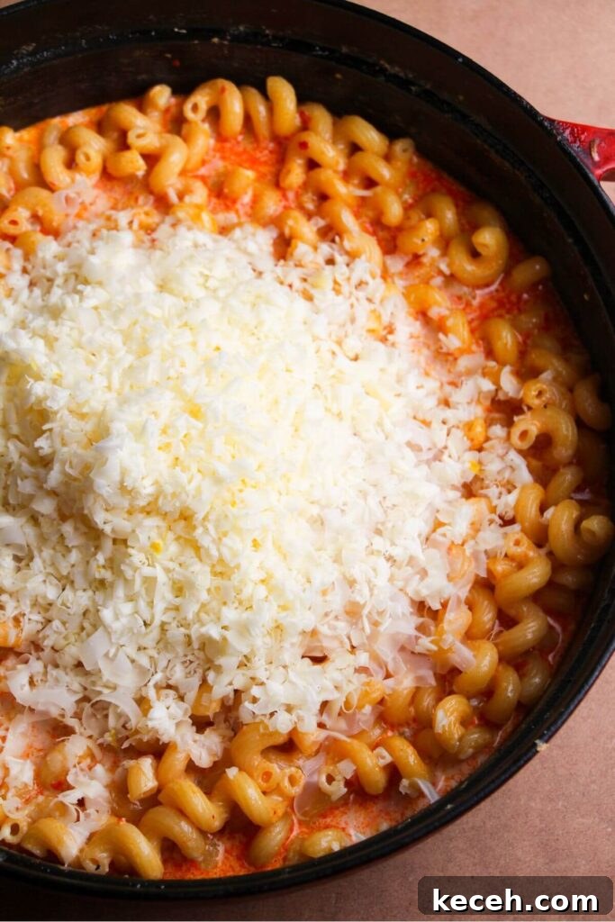 Creamy Spicy One-Pot Mac and Cheese Recipe 8 Grated cheese piled on top of macaroni in a large black skillet.