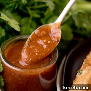 enchilada sauce in a clear jar being scooped out with a spoon