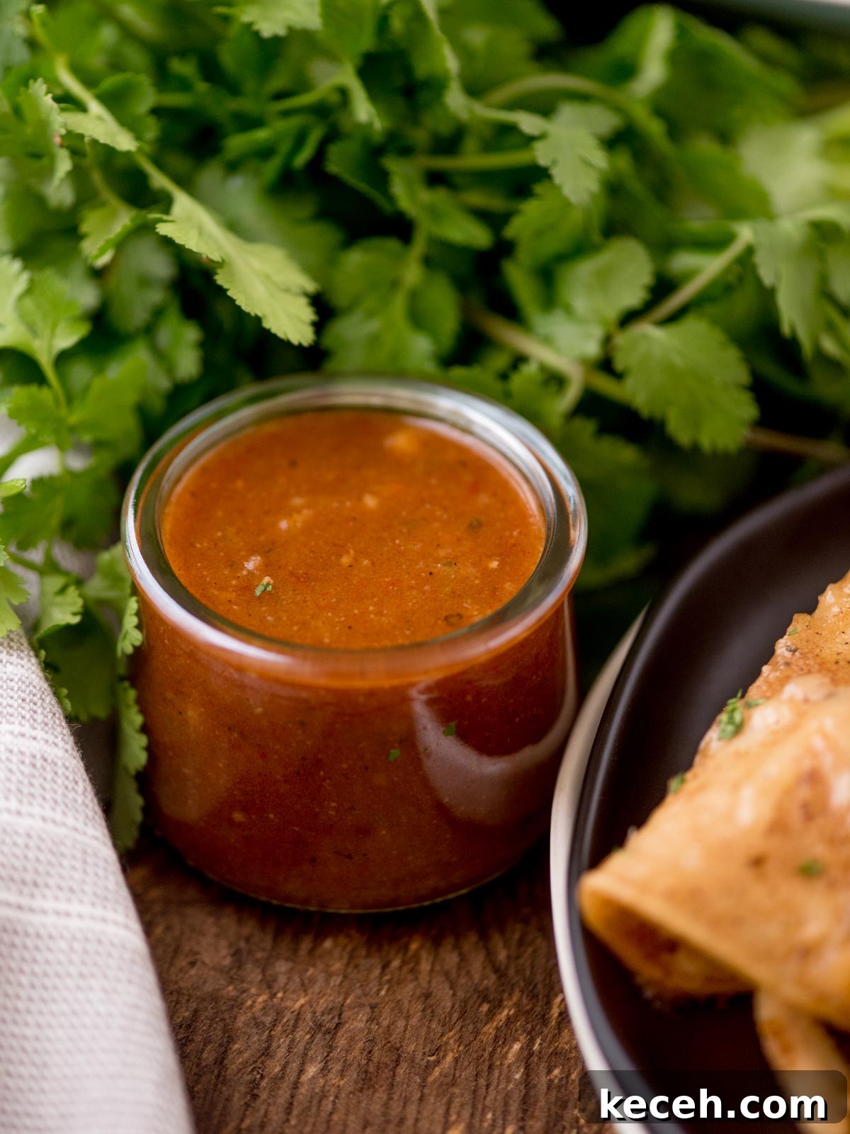 Enchilada sauce in a jar with cilantro bunch in the background