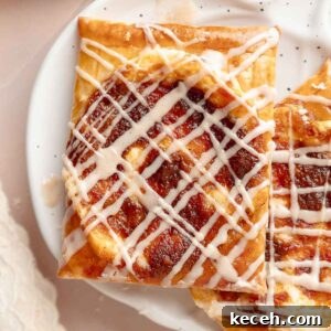 Gluten-Free Pumpkin Cream Cheese Danish Recipe — Starbucks Copycat 15 Close-up of a single pumpkin danish on a white speckled plate. The flaky crust and pumpkin filling are topped with a neat drizzle of icing.