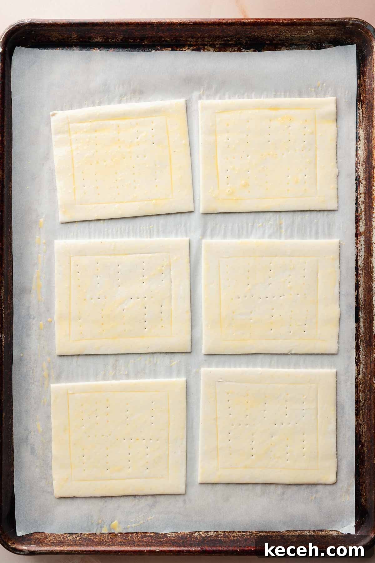 Gluten-Free Pumpkin Cream Cheese Danish Recipe — Starbucks Copycat 5 Raw puff pastry rectangles on a baking sheet lined with parchment paper. Each rectangle is scored and docked in the center, and brushed with egg wash.