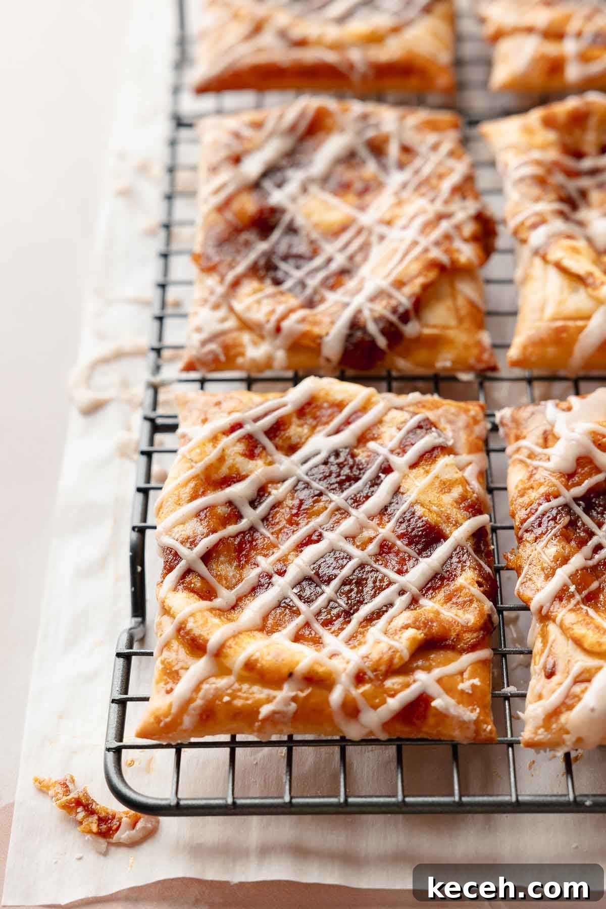 Gluten-Free Pumpkin Cream Cheese Danish Recipe — Starbucks Copycat 10 Freshly baked gluten-free pumpkin danishes on a cooling rack. Each one is drizzled with icing and has golden puff pastry with a spiced pumpkin center.