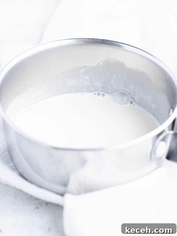 Chocolate Ganache Recipe: Smooth, Glossy Ganache in Minutes 5 Hot cream in a small silver pot.