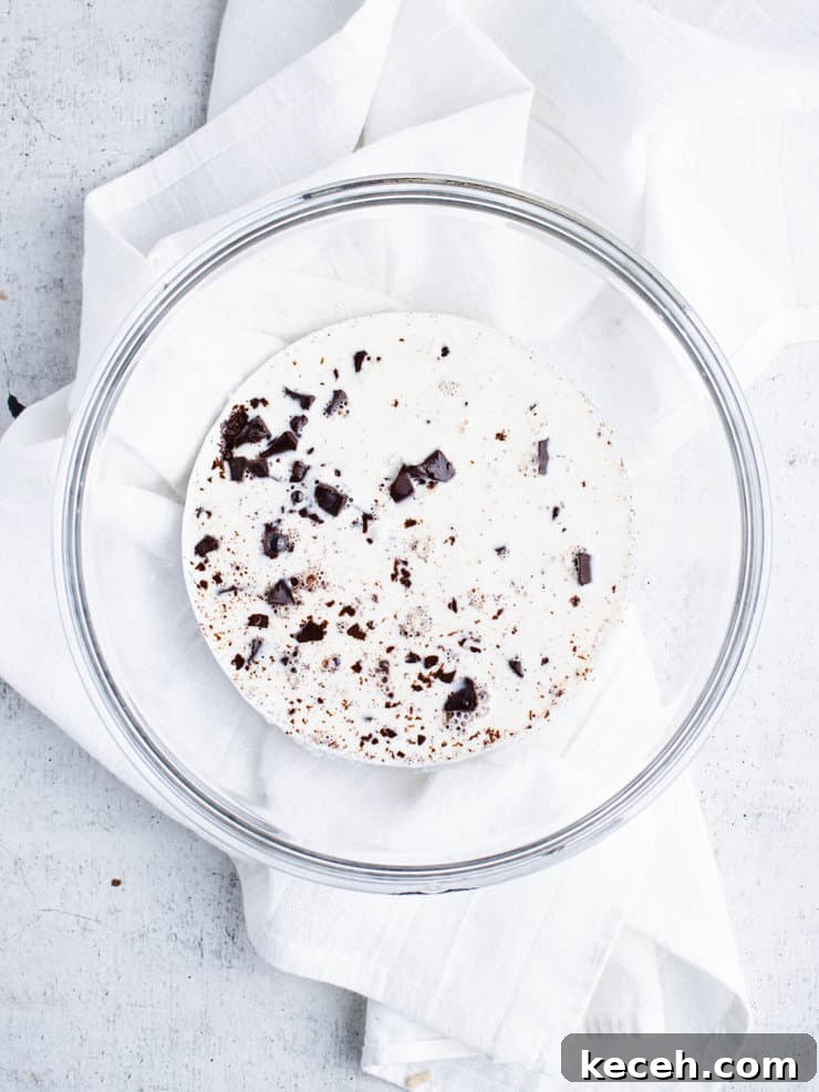 Chocolate Ganache Recipe: Smooth, Glossy Ganache in Minutes 6 Diced chocolate covered with hot cream in a clear bowl.