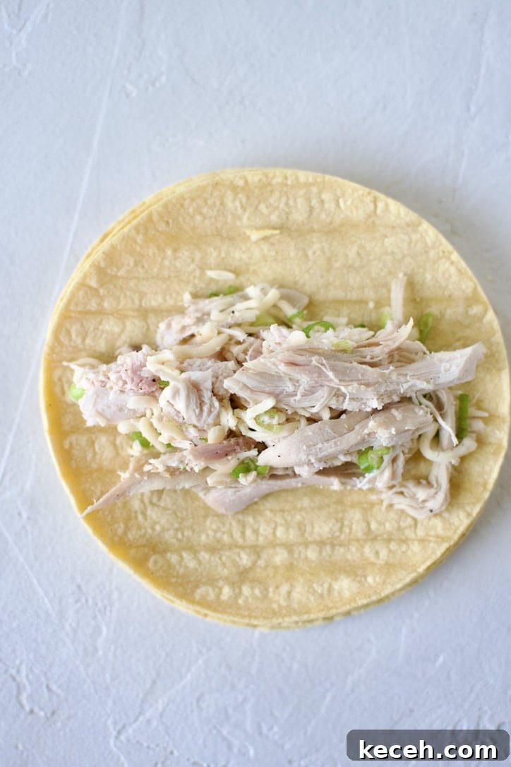 Filling a corn tortilla with the chicken mixture.