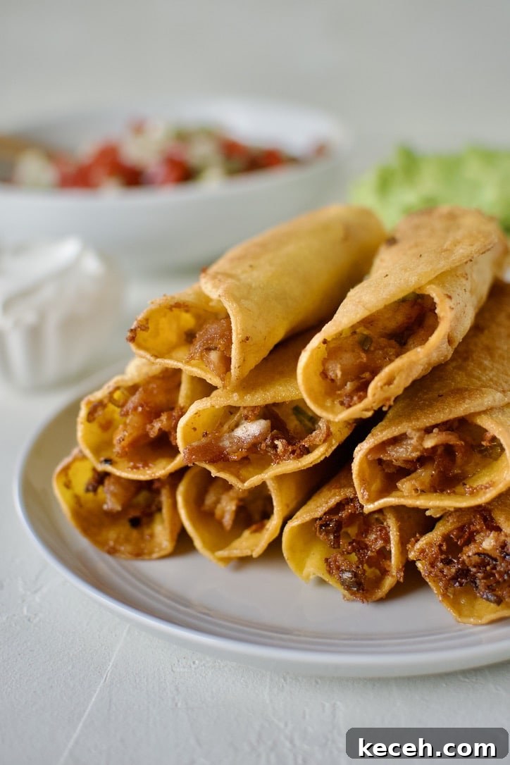 Cooked flautas stacked up on a plate cooling.