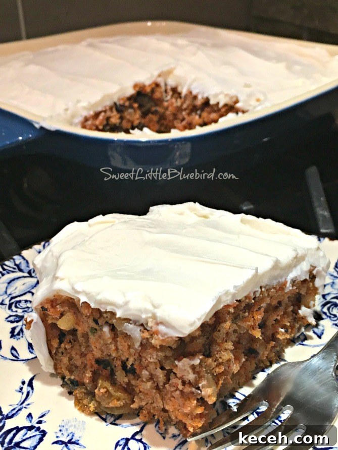 This is a photo of a piece of crazy carrot cake topped with vanilla frosting on a plate with a fork. Behind the plate is the baking dish with the cake.