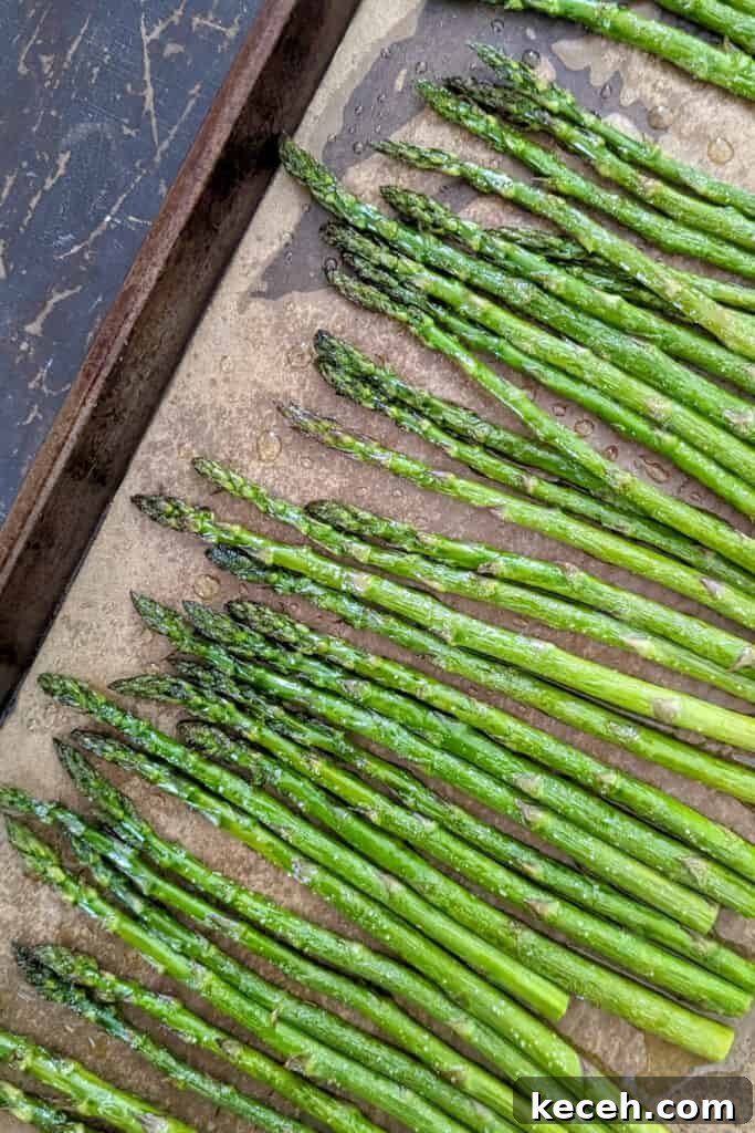 Roasted Asparagus with Fresh Mint Gremolata Recipe 3 A sheet tray with brown parchment paper and on top is vibrant green roasted asparagus.