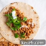 a close up view of a tofu taco topped with micro greens and jalapeno slices.