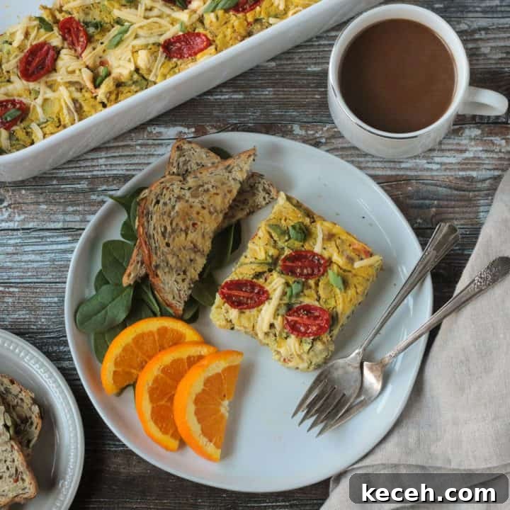 Slice of vegan breakfast casserole on a plate with toast, orange slices, and two forks.