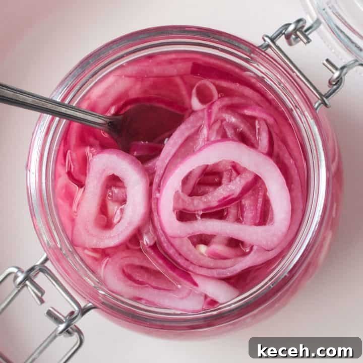 Fork in a an open jar of pickled red onions.