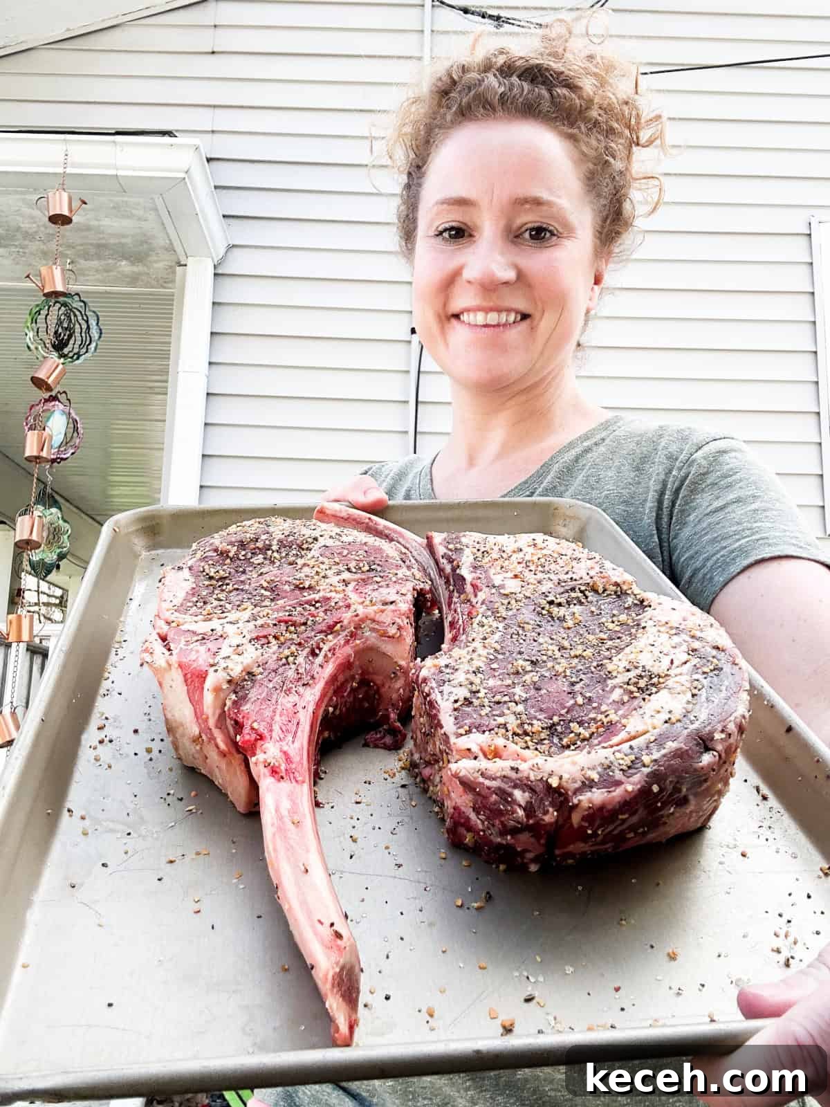 Stef holding sheet pan with Tomahawk steaks before smoking. 