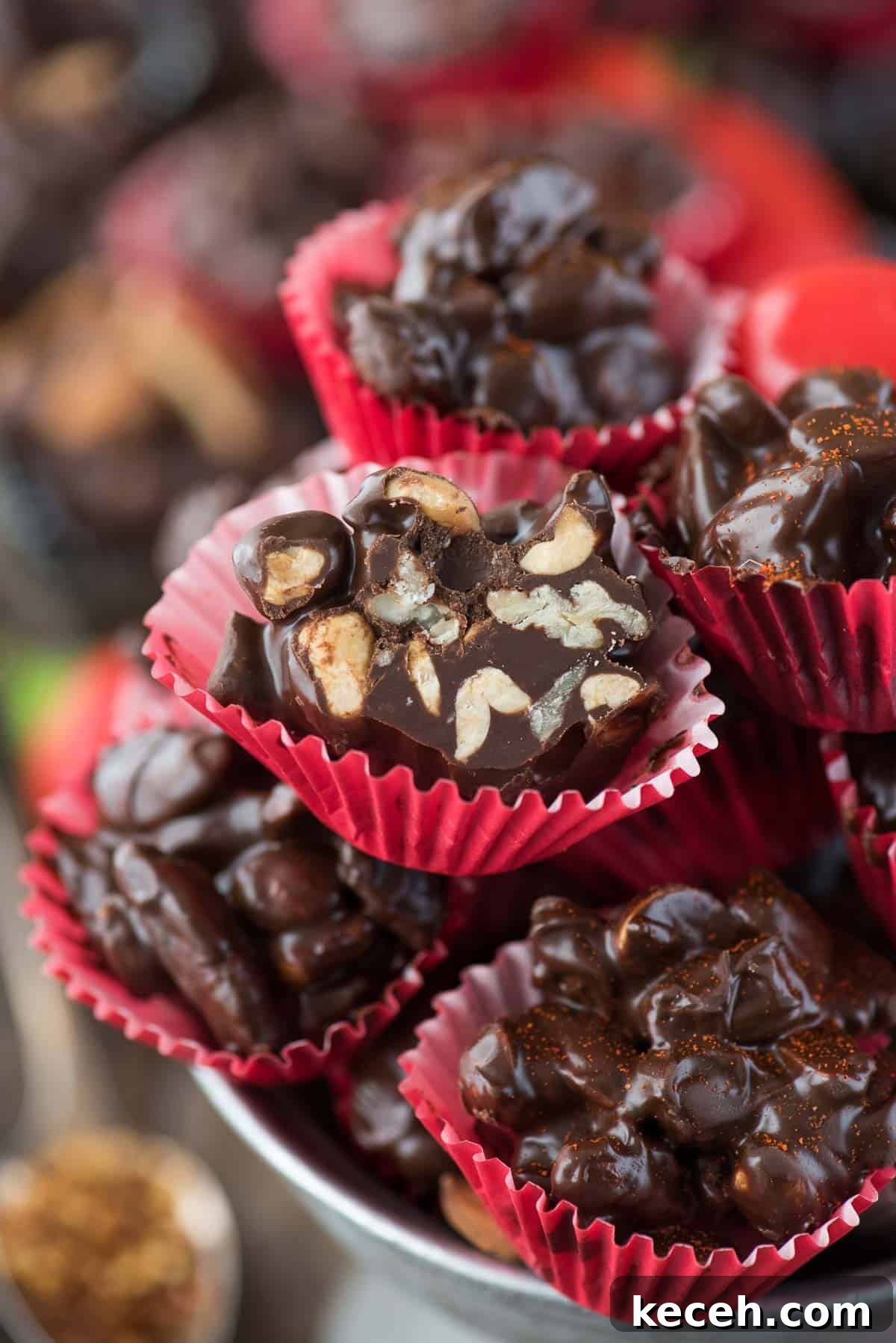 Crock pot or stove top spicy nut clusters! These dark chocolate cayenne nut clusters are popular during the holiday season. Plus there’s notes for making them less spicy or packed with heat! dark chocolate cayenne nut clusters in red mini muffin paper cups