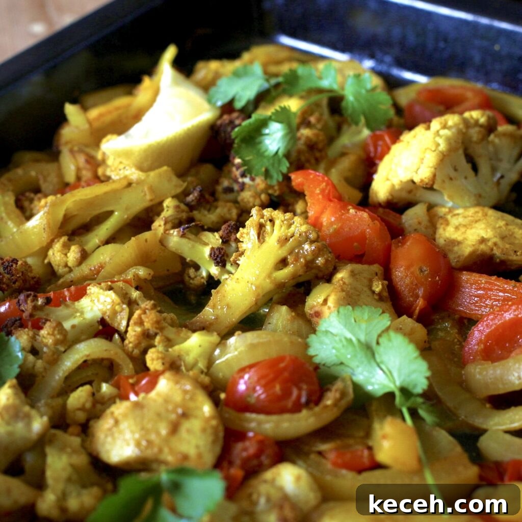 Curried Chicken Tray Bake Recipe from The Slimming Foodie 11 Black baking tray filled with curry roast vegetables and pieces of chicken topped with green coriander leaves
