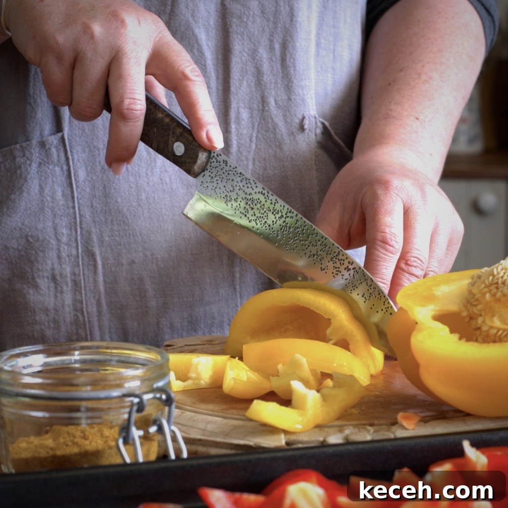 Curried Chicken Tray Bake Recipe from The Slimming Foodie 6 Womans hands slicing a yellow bell pepper on a wooden chopping board