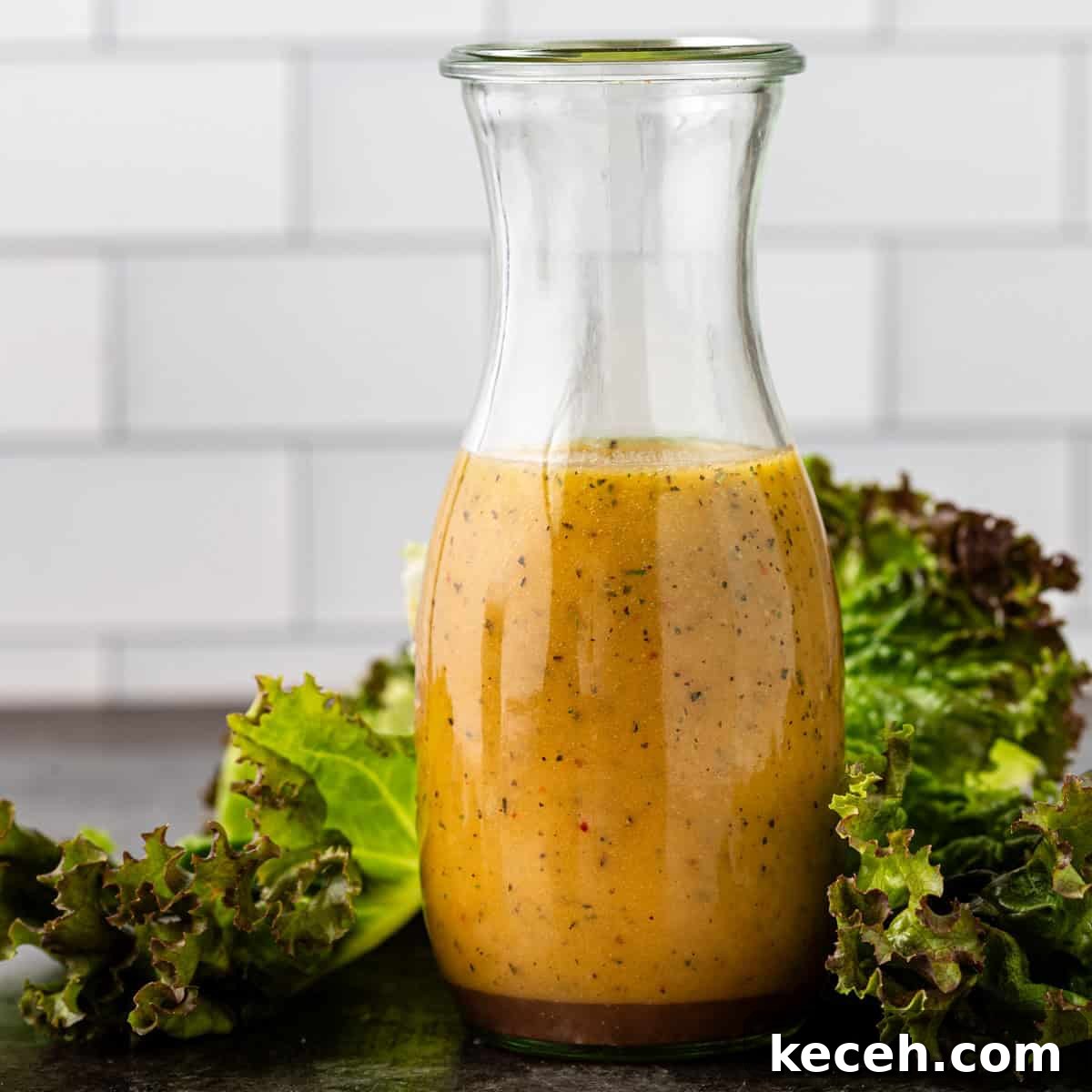 Two Homemade Italian Salad Dressings: Classic & Zesty Variations 2 side view: a large glass jar full of Italian salad dressing with lettuce around the base