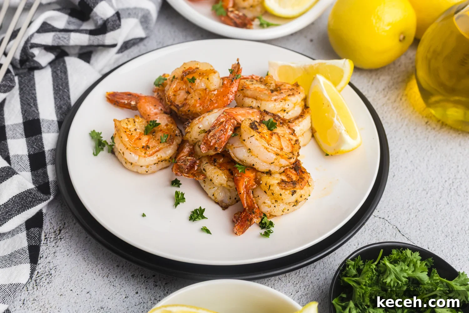 Crispy Blackstone Grilled Shrimp with Garlic Butter Sauce 12 Cooked shrimp served on a white plate with lemon wedges and parsley, ready to eat.