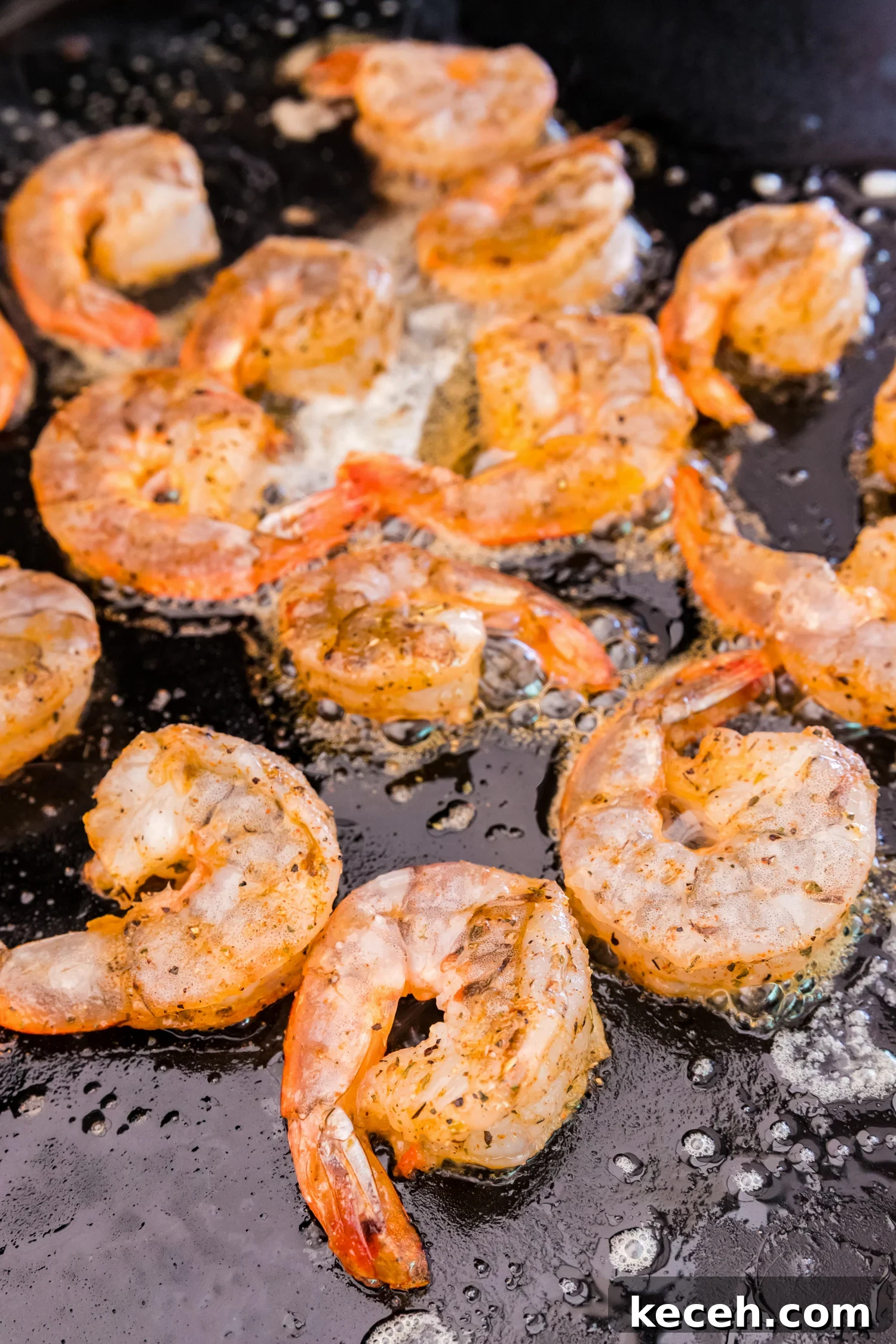 Crispy Blackstone Grilled Shrimp with Garlic Butter Sauce 9 Shrimp sizzling on a hot griddle in melted butter, beginning to cook.